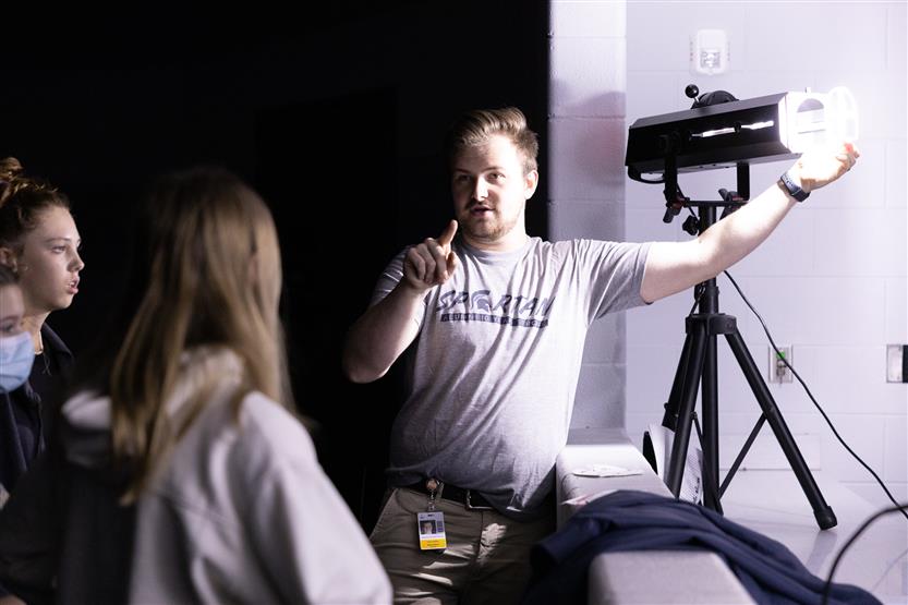 A teacher uses a stage light in front of students